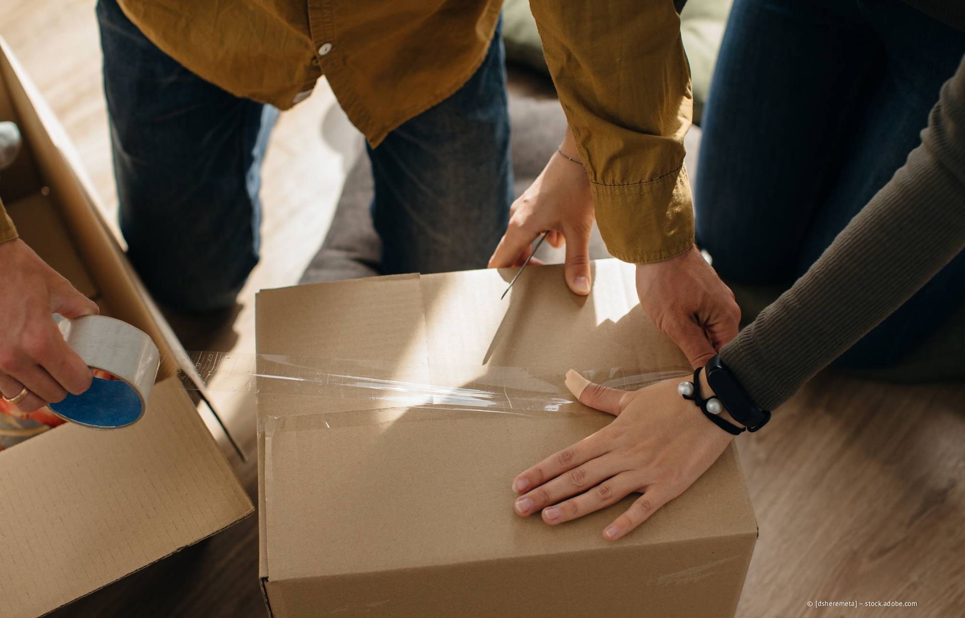 Leute packen einen Karton und kleben ihn zu.