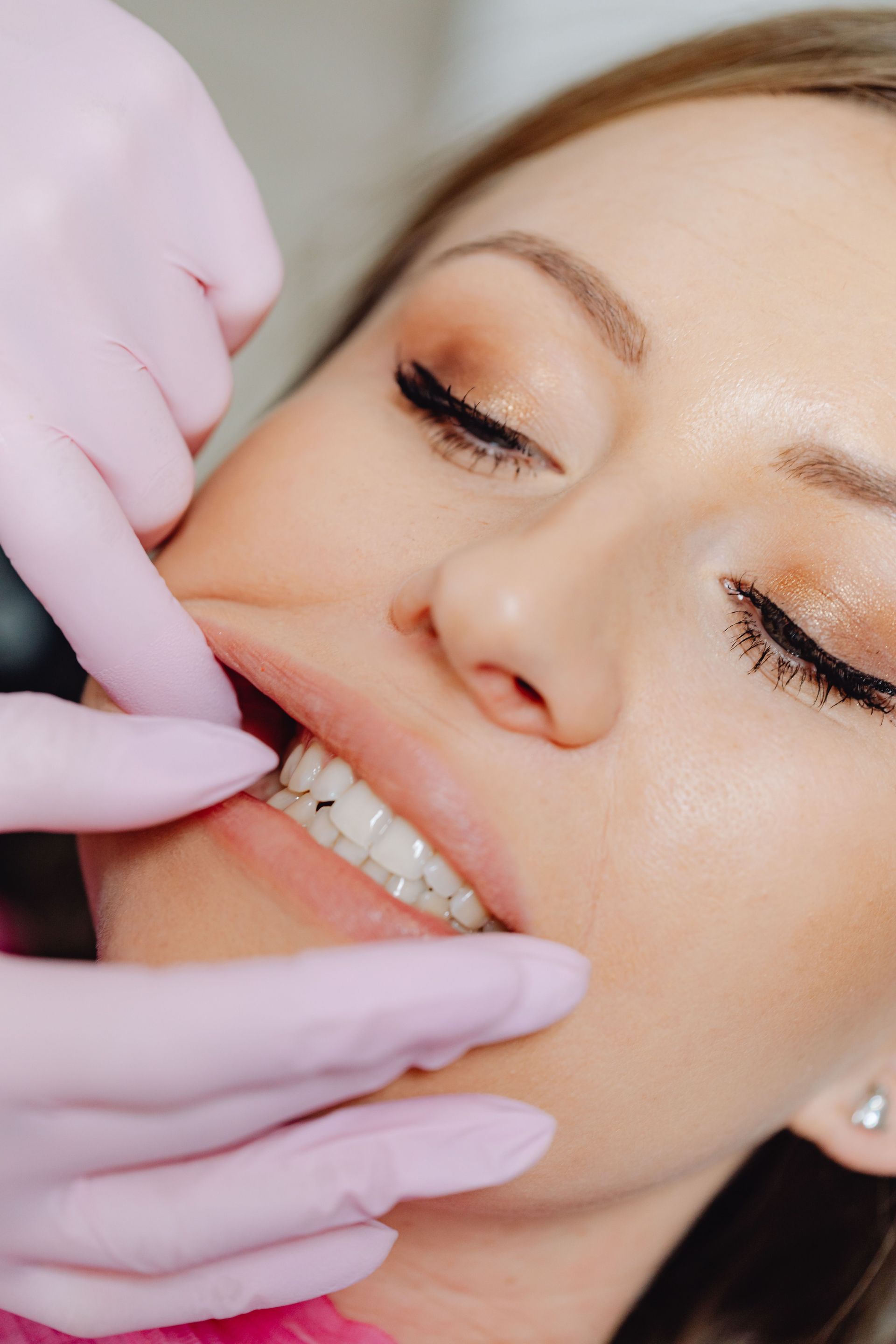 Mujer recibiendo un masaje facial con manos tocando suavemente su rostro, en un entorno de spa.