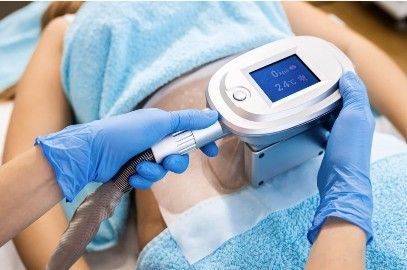 Persona recibiendo tratamiento en un spa. Un técnico utiliza un dispositivo en la espalda del paciente, en una sala blanca.