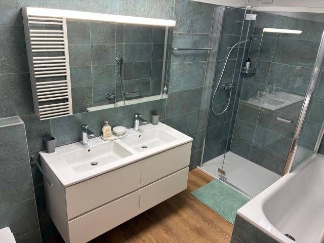 Modernes Badezimmer mit Doppelwaschbecken, Dusche und Badewanne. Türkisfarbene Fliesenwände.