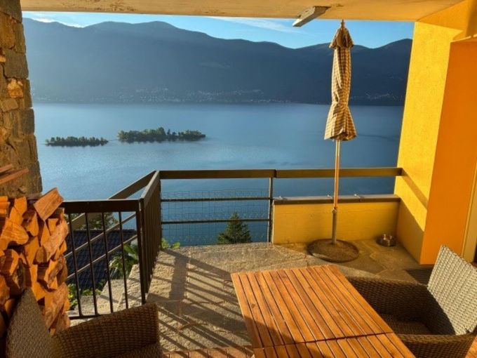 Wohnzimmer mit Kamin, Essbereich und offener Küche; Holzmöbel, neutrale Wände, Sonnenlicht.