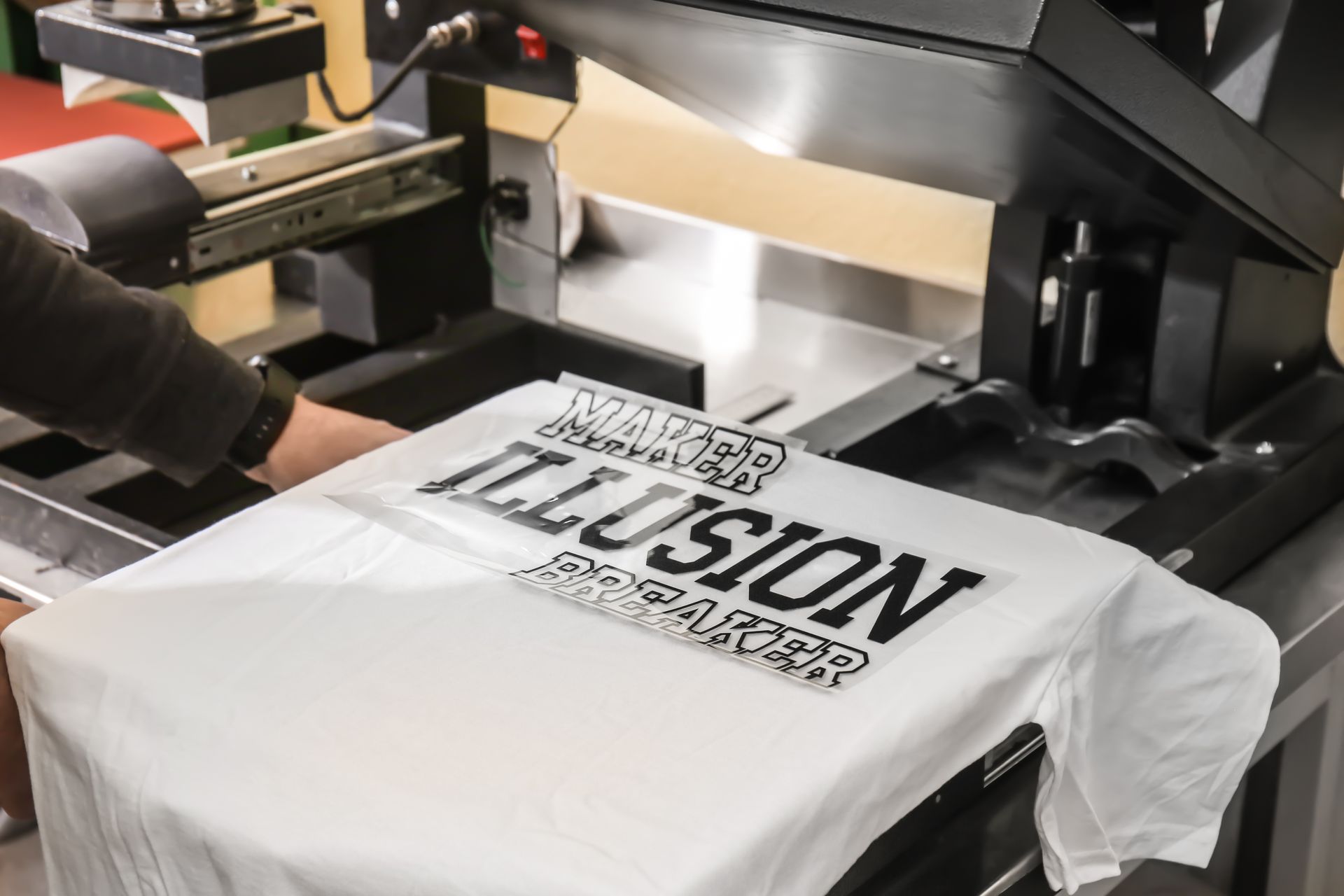 Travaux de flocage en cours avec transfert de message noir sur t-shirt blanc