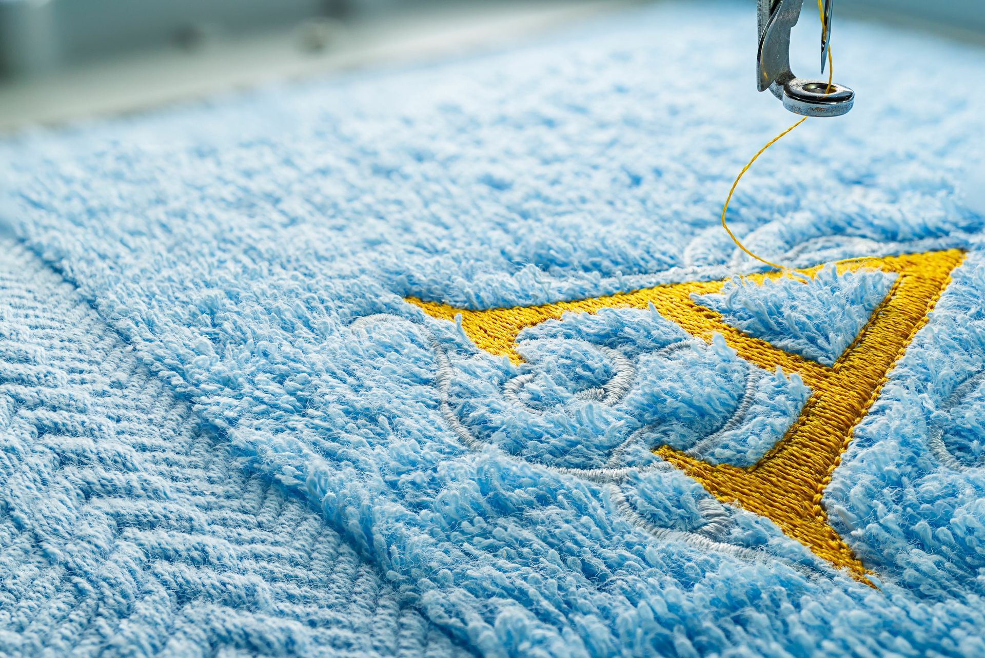 Broderie de la lettre A de couleur jaune sur tissu-éponge bleu ciel