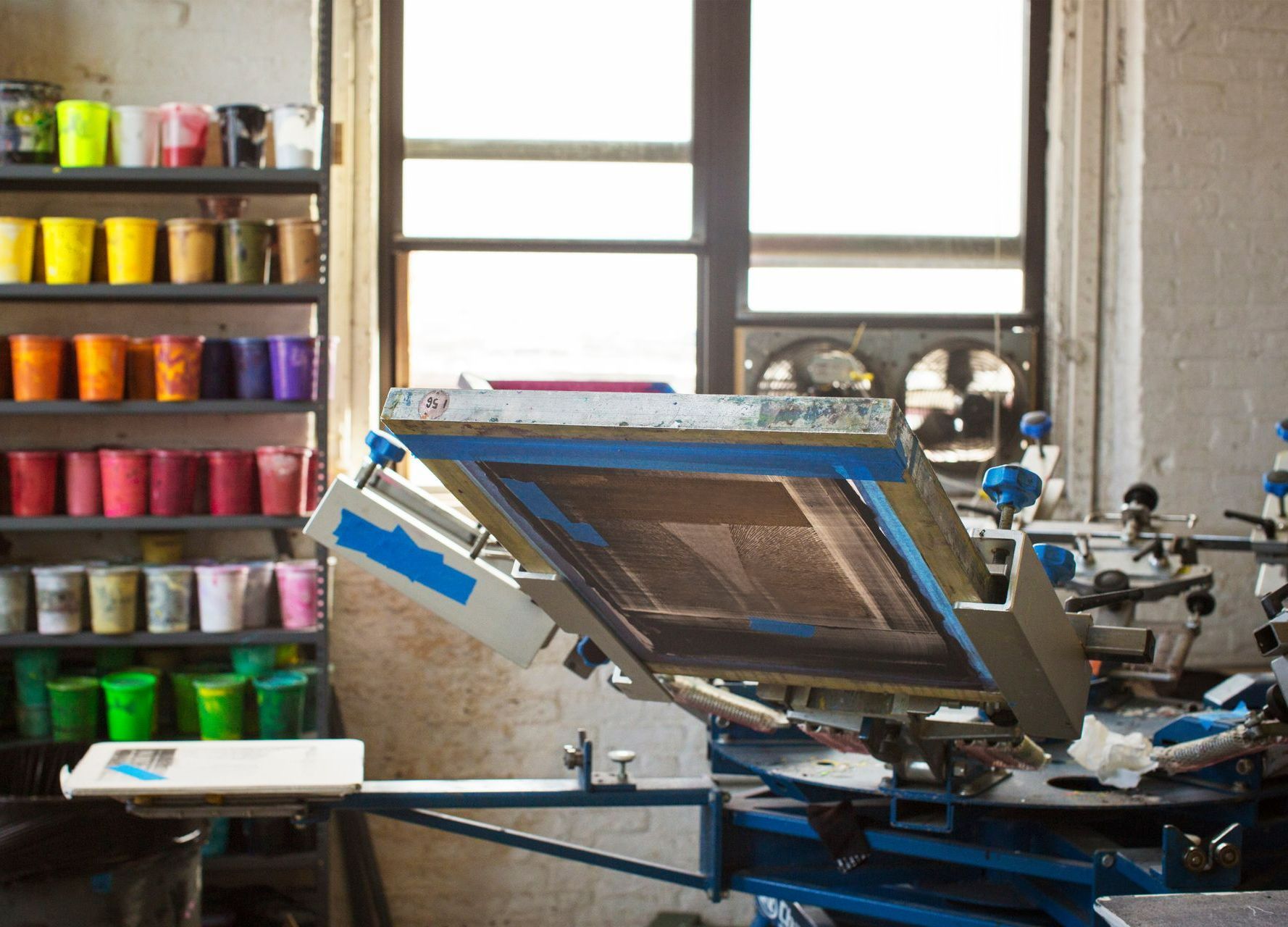 Caroussel de sérigraphie et étalage de pot de couleurs en arrière plan