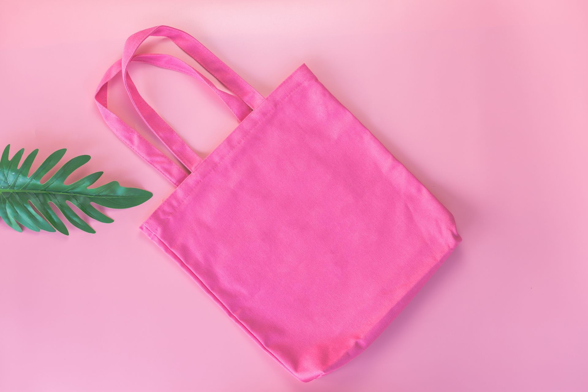 Tote bag rose fuchsia posé sur fond rose clair