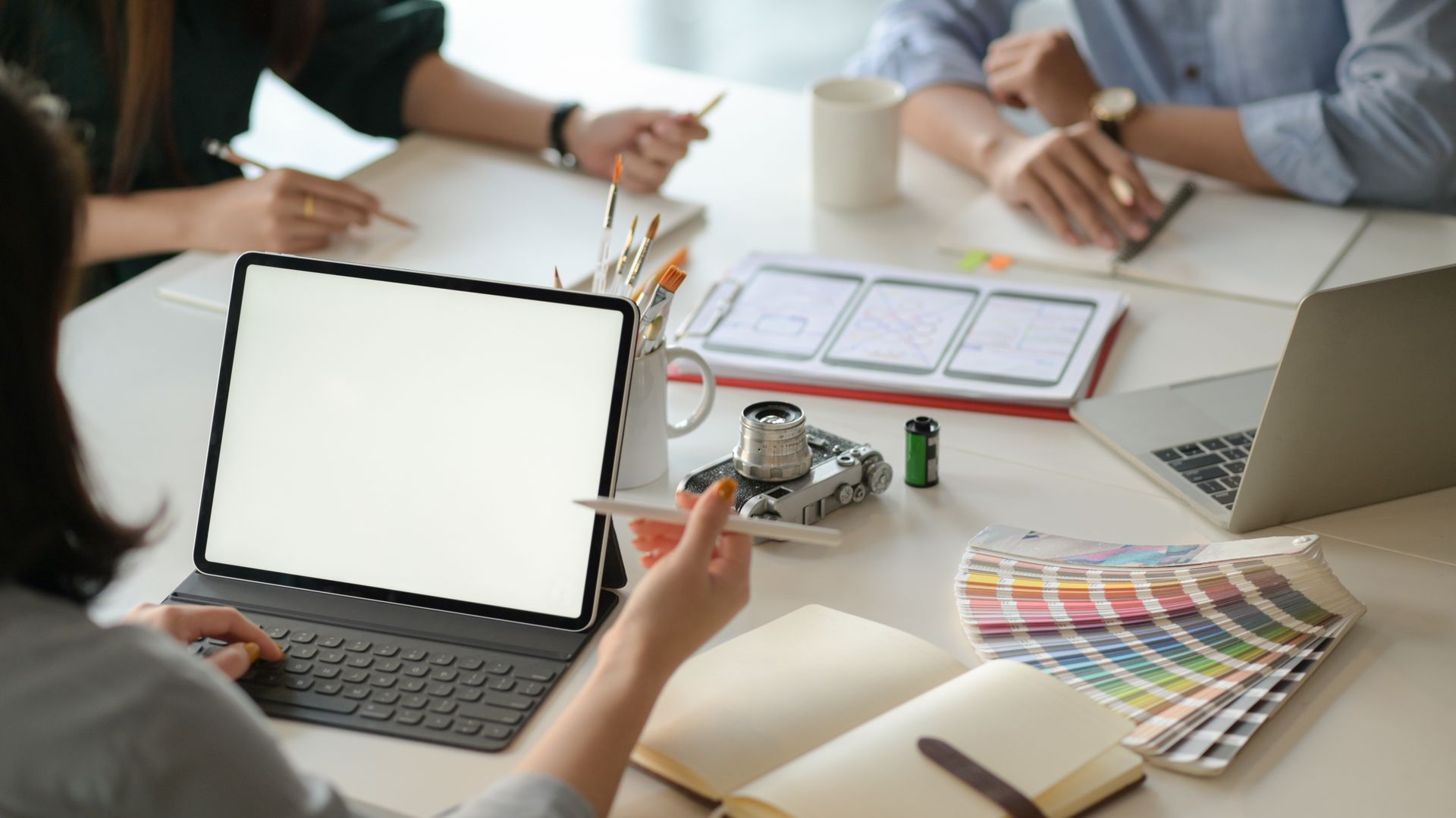 Personnes échangeant autour d'une table de bureau avec ordinateur et nuancier de couleur