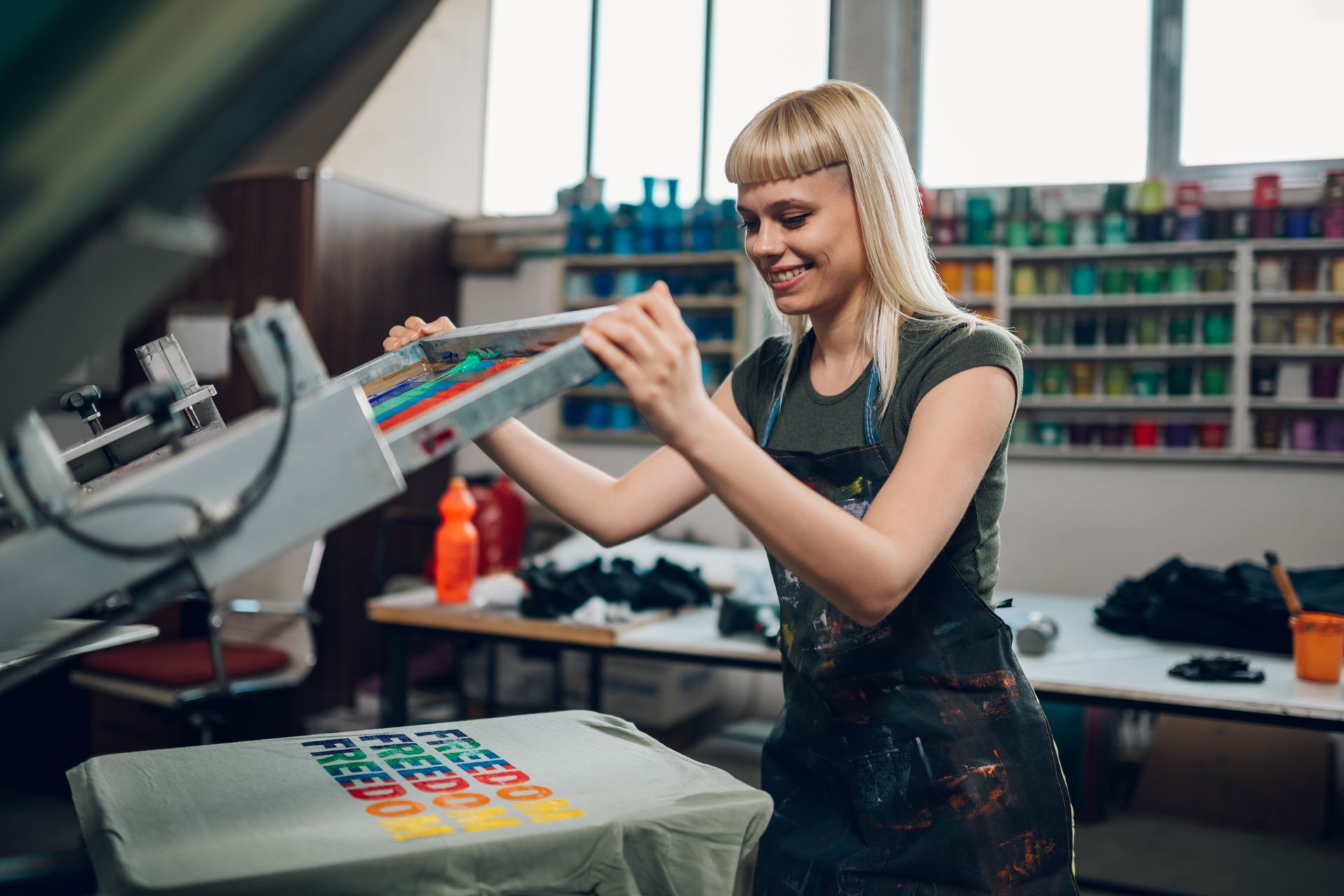 Femme souriante réalisant des travaux de sérigraphie sur t-shirt