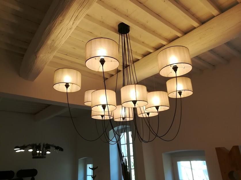 Un lustre chaleureux avec plusieurs abat-jour crème est suspendu à un plafond à poutres apparentes dans une pièce confortable.
