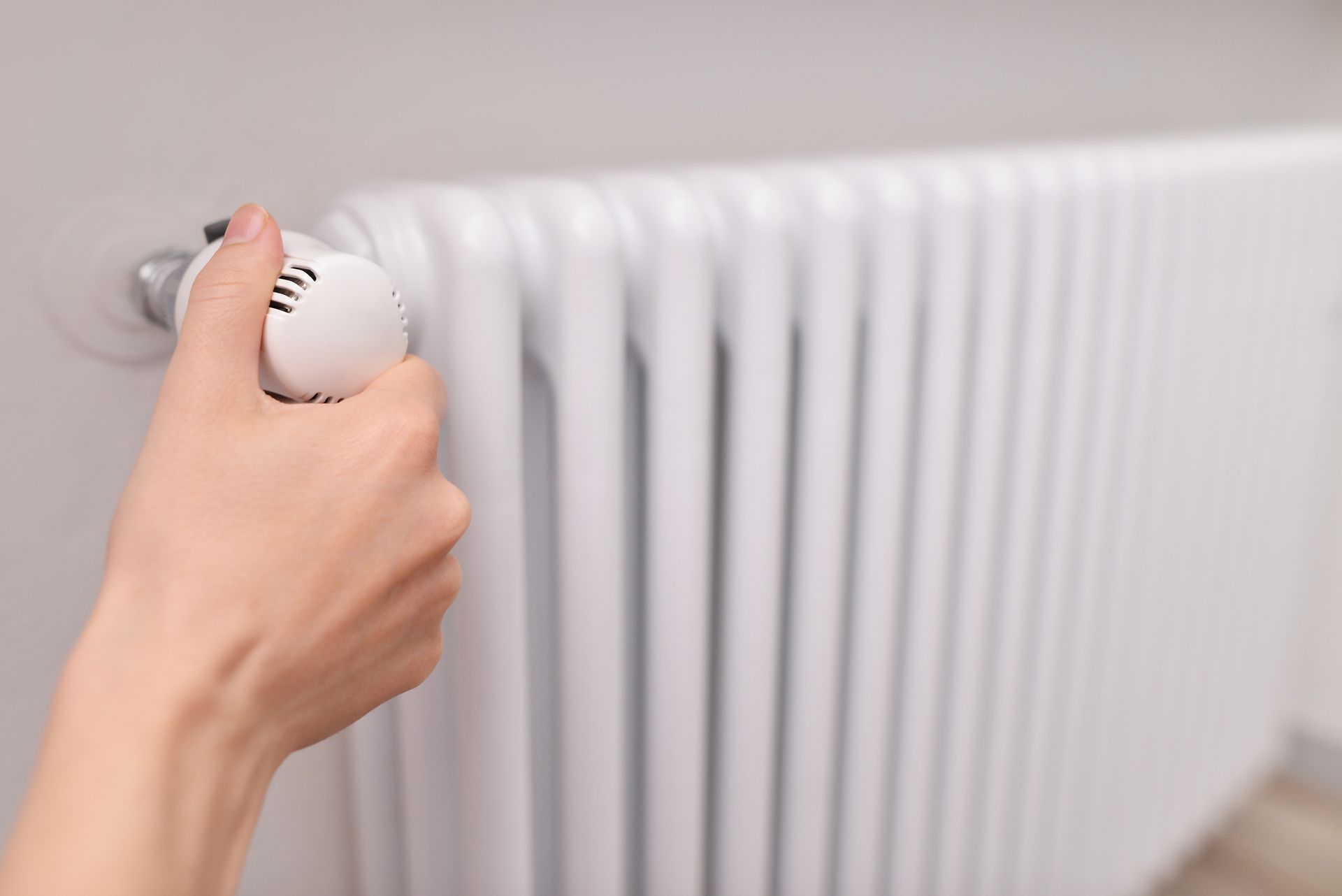 Manipulation manuelle d'un robinet de radiateur blanc dans une pièce