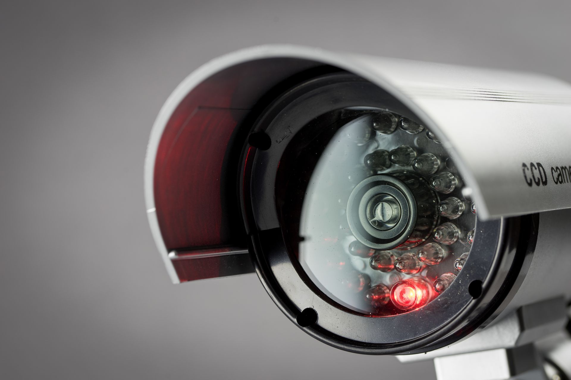 Caméra de sécurité blanche avec LED rouge, gros plan sur fond gris