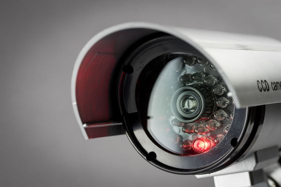 Caméra de sécurité blanche avec LED rouge, gros plan sur fond gris