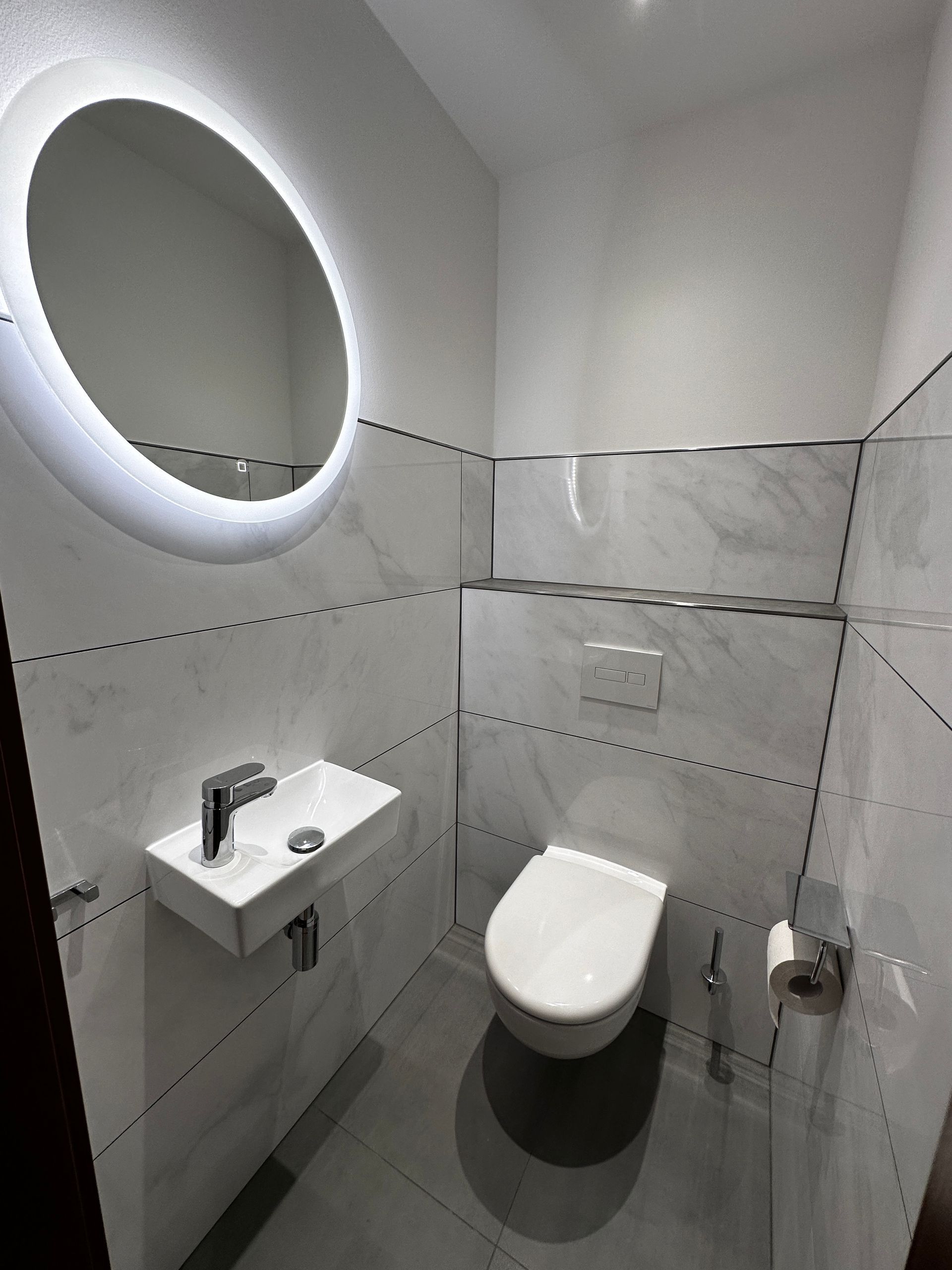 Ein Badezimmer mit Toilette, Waschbecken und Spiegel