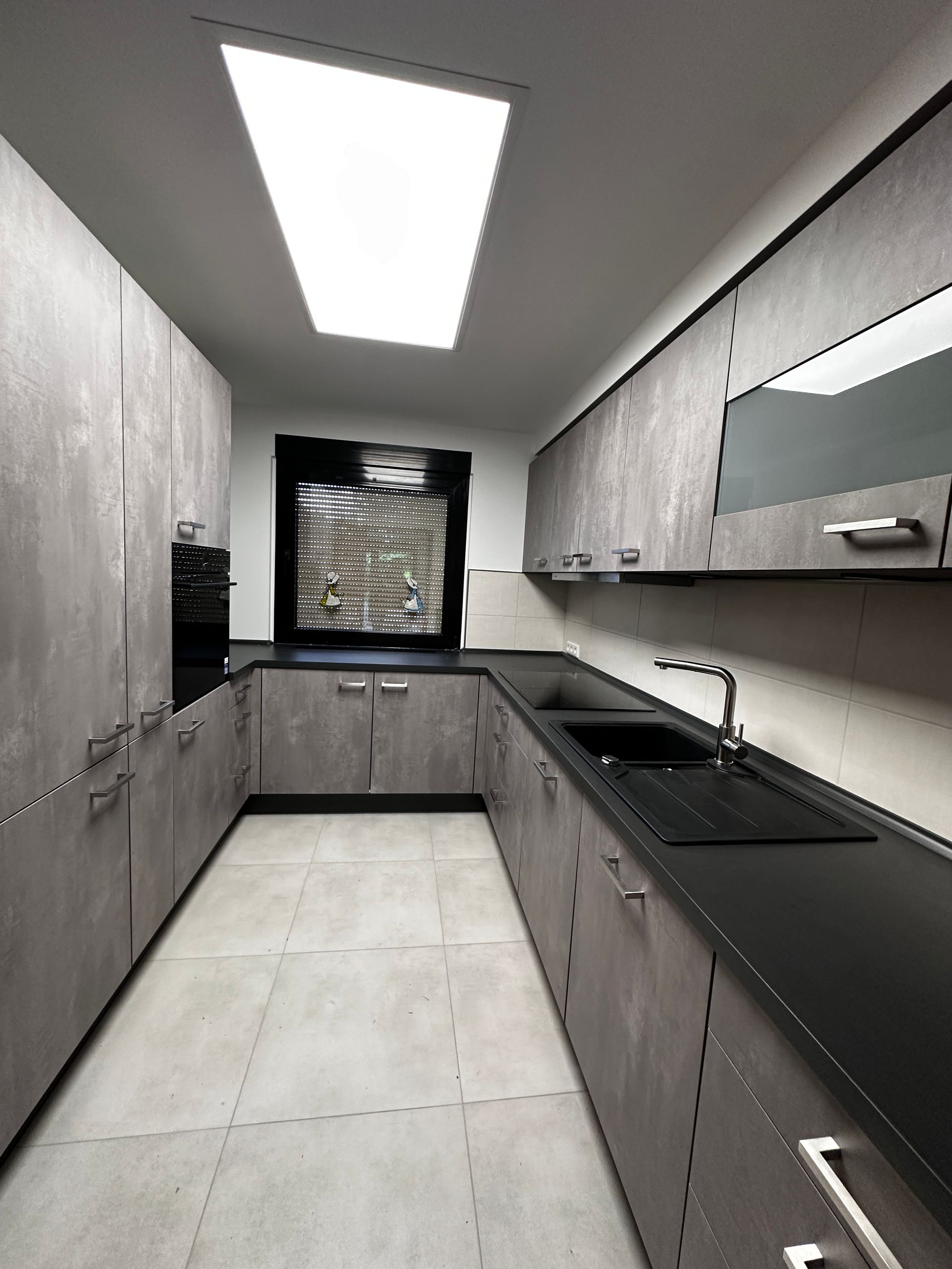 Eine Küche mit grauen Schränken und schwarzen Arbeitsplatten