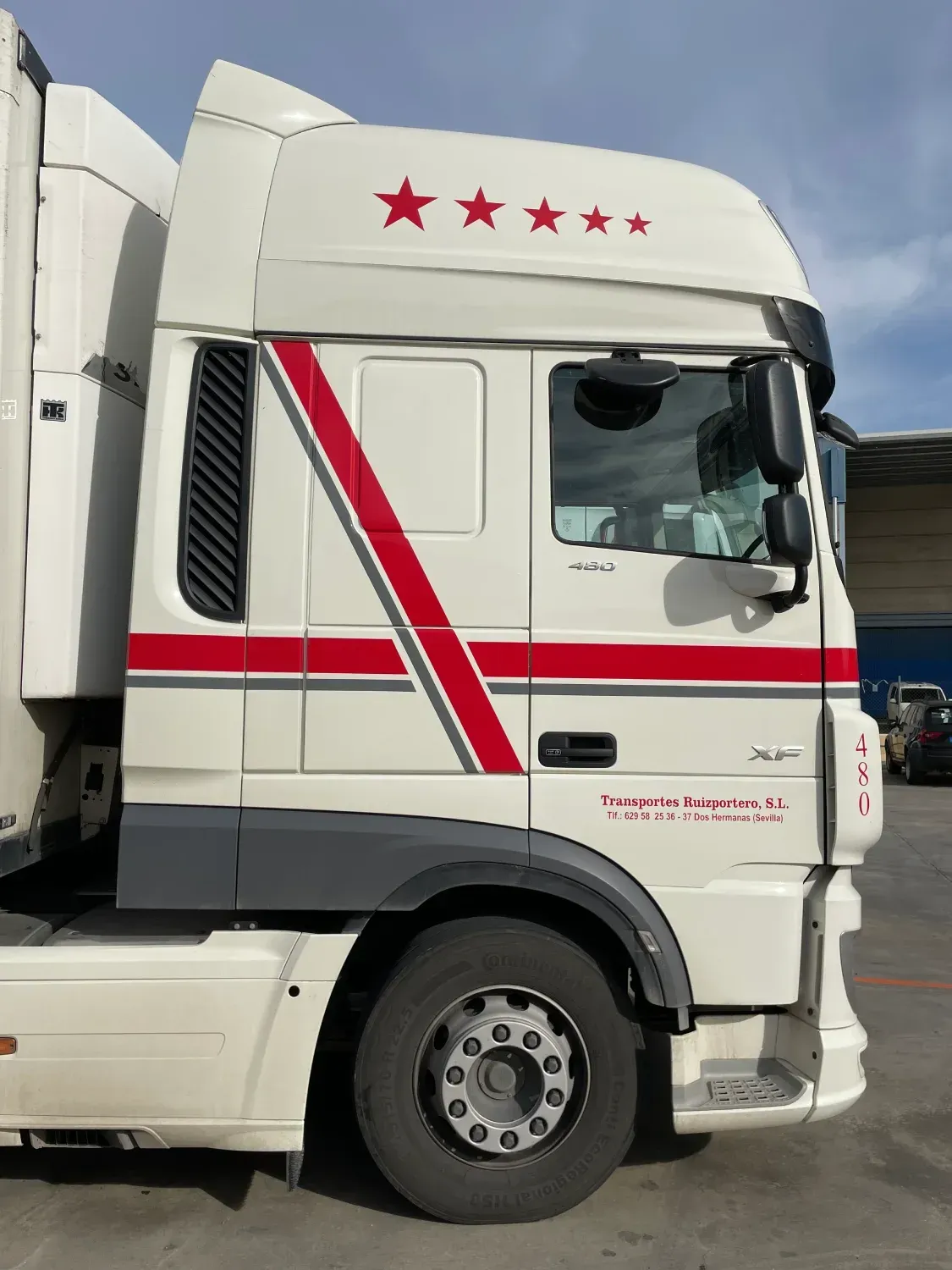 Un camión blanco con rayas rojas y estrellas en el costado está estacionado en un estacionamiento.