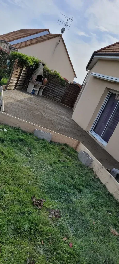 Une maison avec une antenne sur le toit, une terrasse en béton et un jardin.