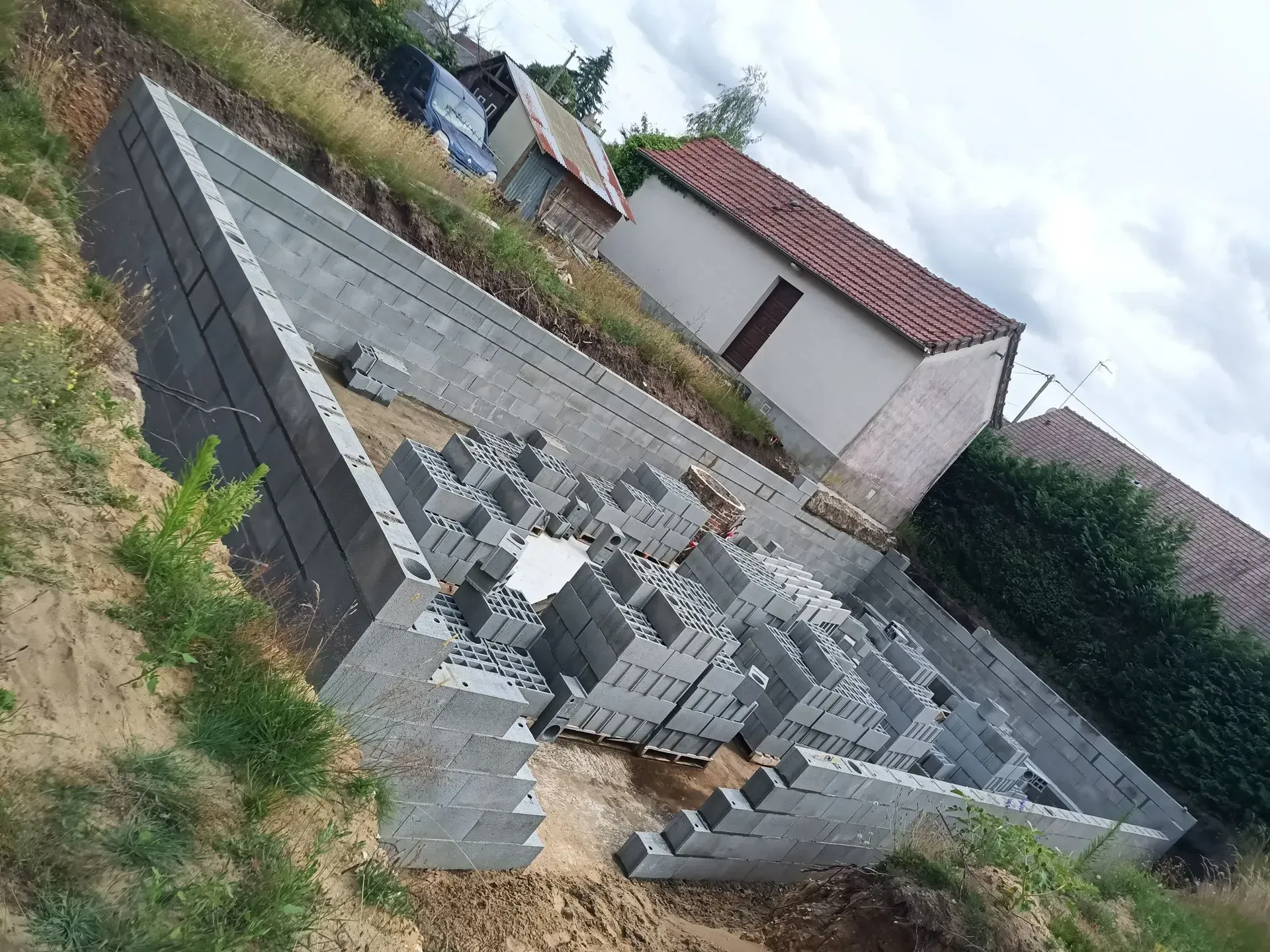 Fondations en blocs de béton gris avec d'autres maisons et de la végétation en arrière-plan.