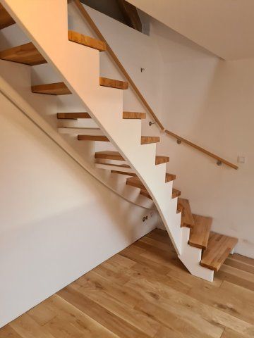 Holztreppe mit weißen Setzstufen, Holzhandlauf und hellem Holzboden.