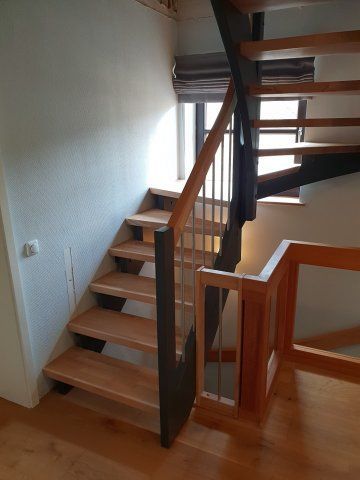 Holztreppe mit Metall- und Holzgeländer, die zu einem Fenster führt.
