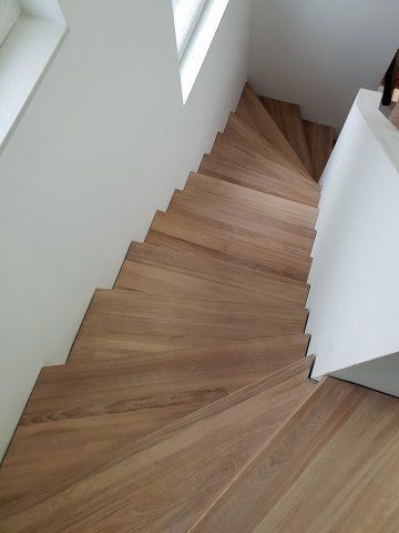 Hölzerne Wendeltreppe mit weißen Wänden und Fenster.