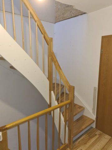 Holztreppe mit weißem Geländer und Holzgeländer. Treppenhaus, das nach oben zu einer Tür führt.