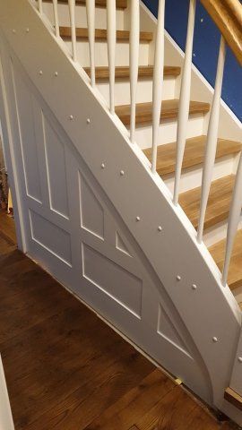 Holztreppe mit weißem Geländer, hellen Holzstufen und getäfelter Seitenwand.