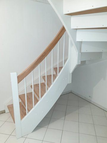 Holztreppe mit weißen Setzstufen, Handlauf und Balustern. Trittstufen aus hellem Holz.