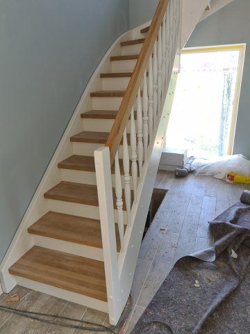 Treppe mit Holzstufen und weißem Geländer vor einer blauen Wand und einem Fenster.