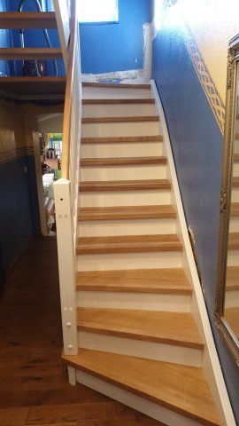 Holztreppe mit weißen Setzstufen vor blauen und gelben Wänden.