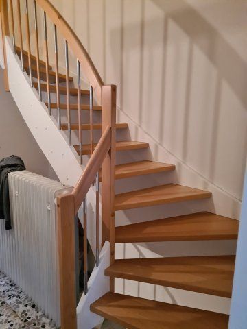 Holztreppe mit geschwungener Spitze und Metallgeländer.