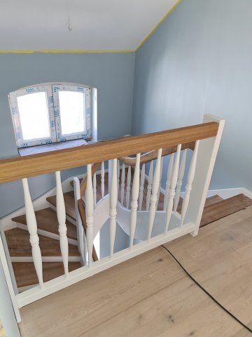 Treppe mit Holzstufen und Geländer, weißem Geländer und blauer Wand. Heller Holzboden.