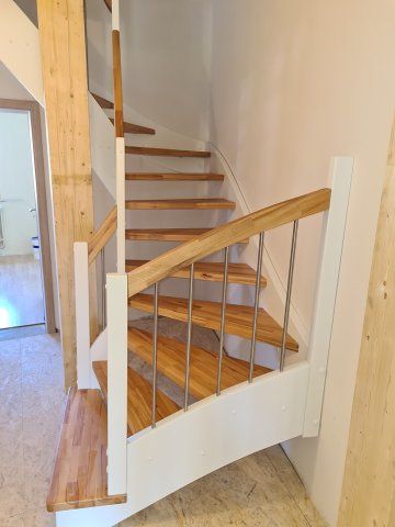 Holztreppe mit weißem Geländer und Metallbalustern; Stufen aus Naturholz.