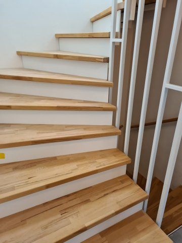 Holztreppe mit weißen Setzstufen und Geländer.