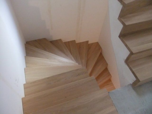 Nach oben geschwungene Holztreppen, umgeben von weißen Wänden.