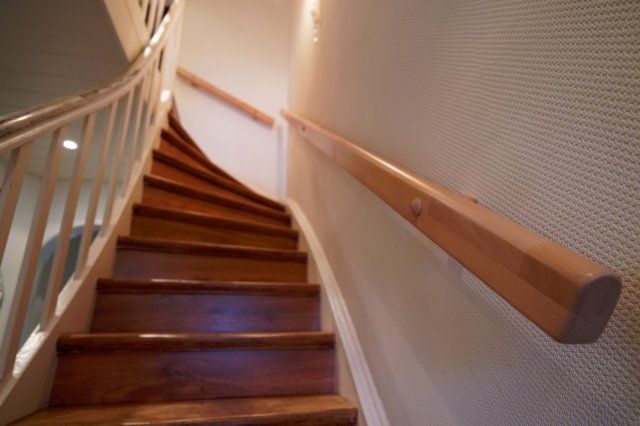 Nach oben führende geschwungene Holztreppe mit zwei Handläufen.