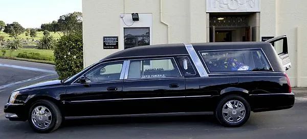 Un coche negro está aparcado delante de un edificio.