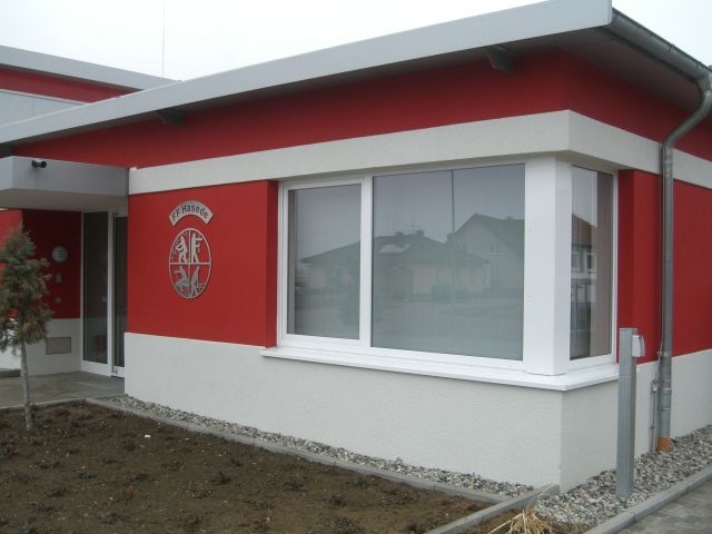 Ein rot-weißes Gebäude mit einem großen Fenster und einem kleinen Logo.