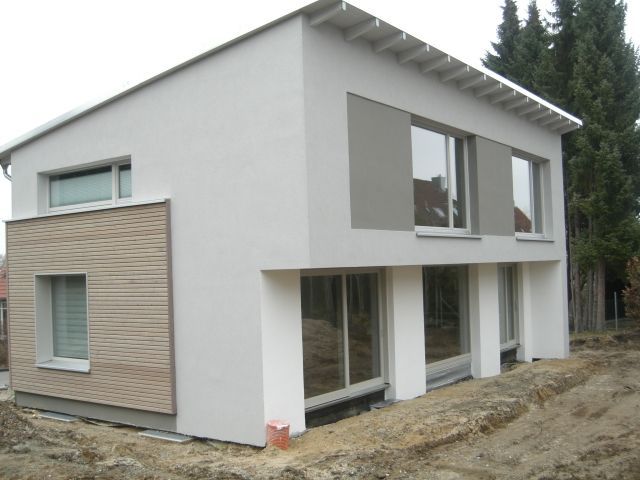 Modernes zweistöckiges Haus mit weißem Stuck, Holzverkleidung und großen Fenstern; Baustellenlage.