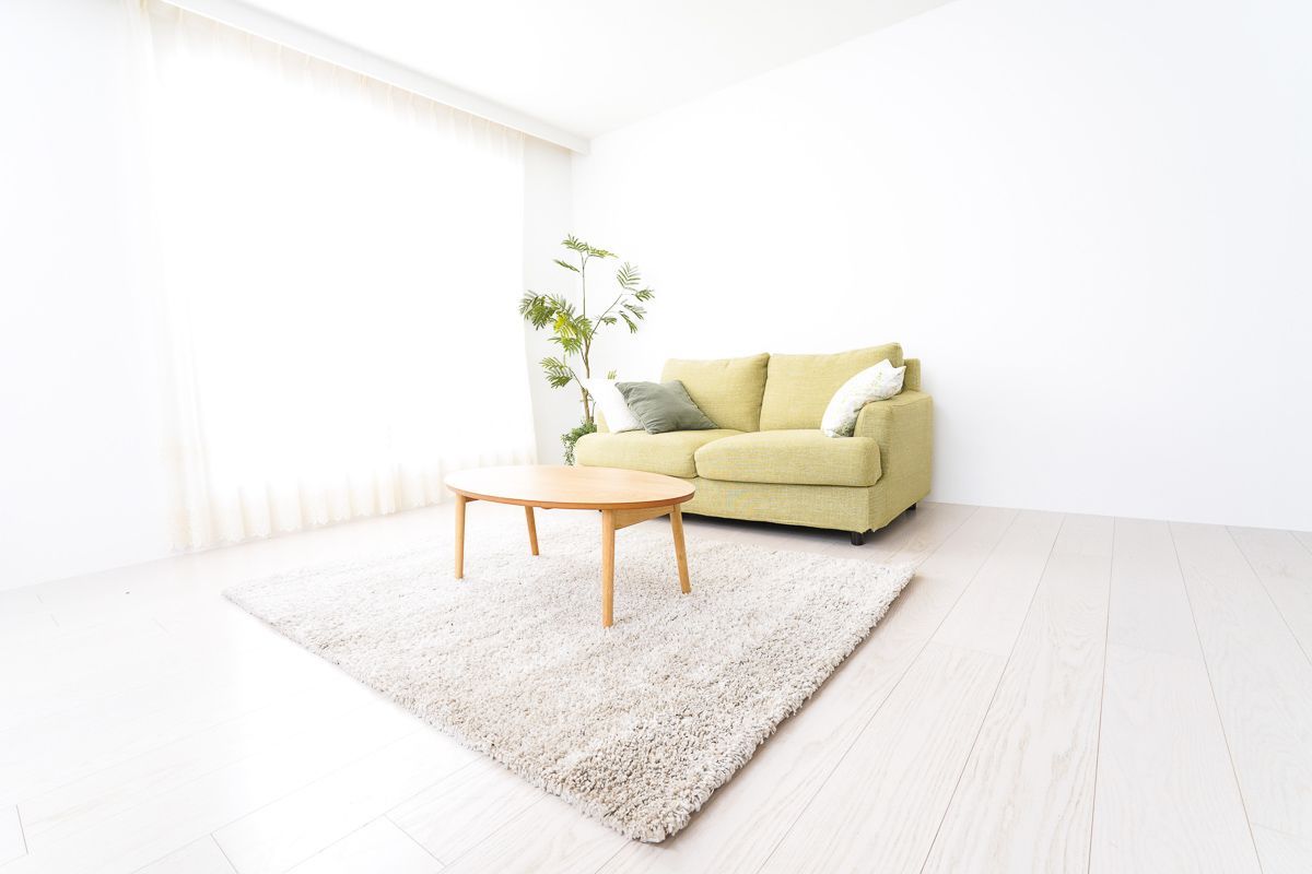 ein Wohnzimmer mit einer grünen Couch , einem Tisch und einem Teppich - Bodenbeläge von Koke Raumausstattung - Tobias Liebrand - vor Ort in Senden und Lüdinghausen