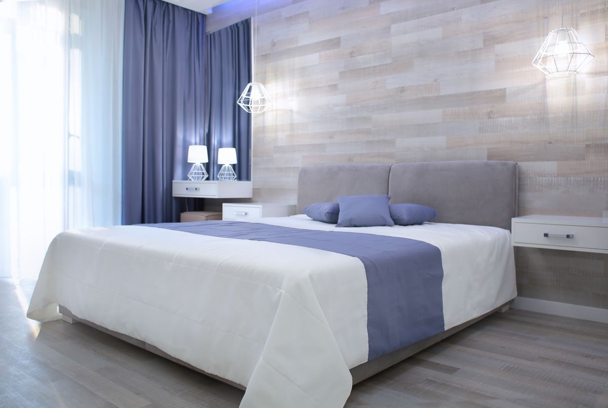 ein Schlafzimmer mit einem Bett und einer Holzwand - Gardinen von Koke Raumausstattung - Tobias Liebrand - vor Ort in Senden und Lüdinghausen