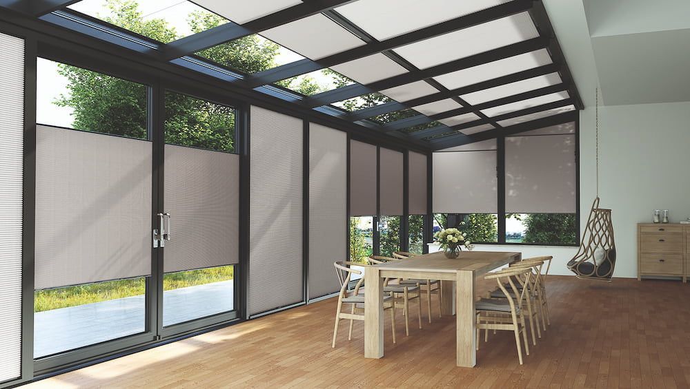 ein Esszimmer mit einem Tisch und Stühlen und vielen Fenstern - Sonnenschutz von Koke Raumausstattung - Tobias Liebrand - vor Ort in Senden und Lüdinghausen