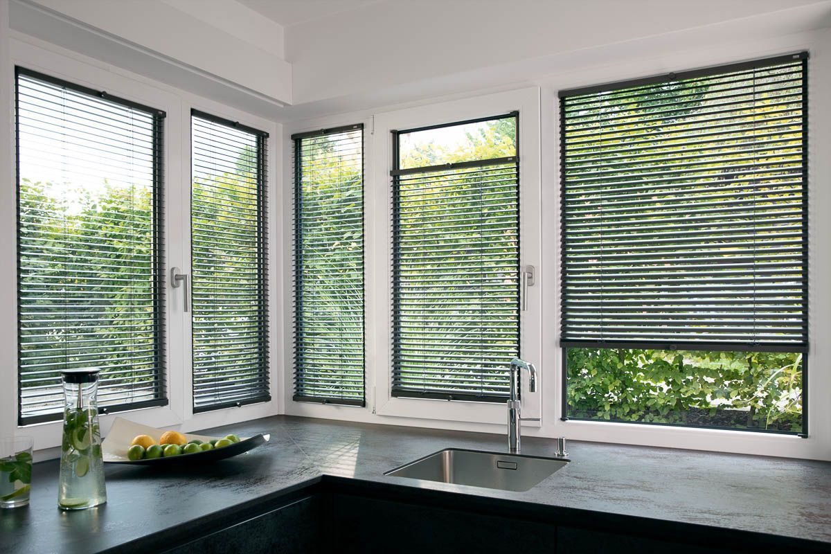 eine Küche mit einem Spülbecken und vielen Fenstern mit Jalousien - Sonnenschutz von Koke Raumausstattung - Tobias Liebrand - vor Ort in Senden und Lüdinghausen