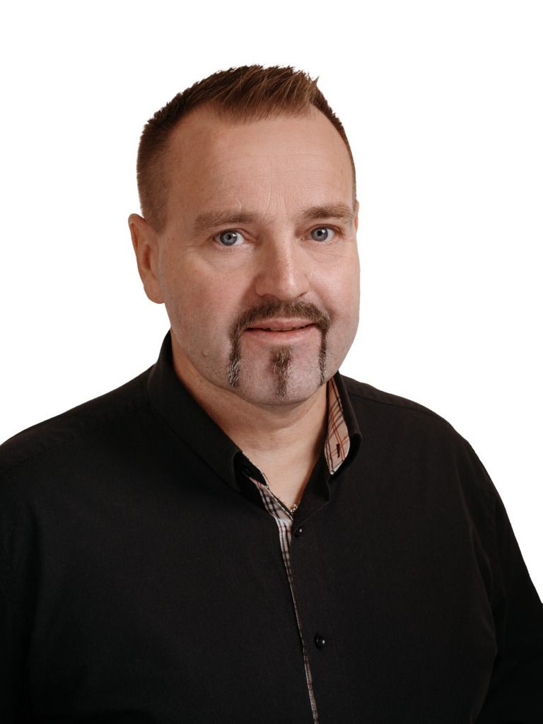 Muotokuva miehestä mustassa paidassa valkoista taustaa vasten
