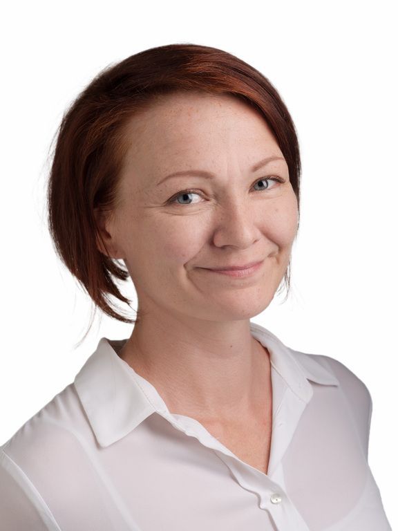 Hymyilevä lyhytkarvainen nainen valkoisessa puserossa valkoisella taustalla
