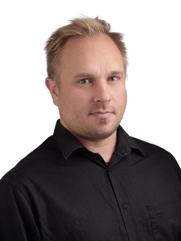 Muotokuva miehestä mustassa paidassa valkoista taustaa vasten