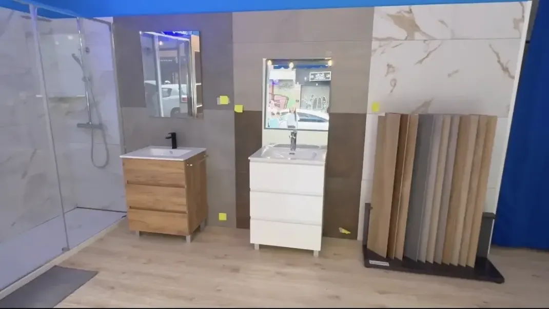 Exposición de baños con tocadores, espejos, muestras de azulejos y una cabina de ducha.