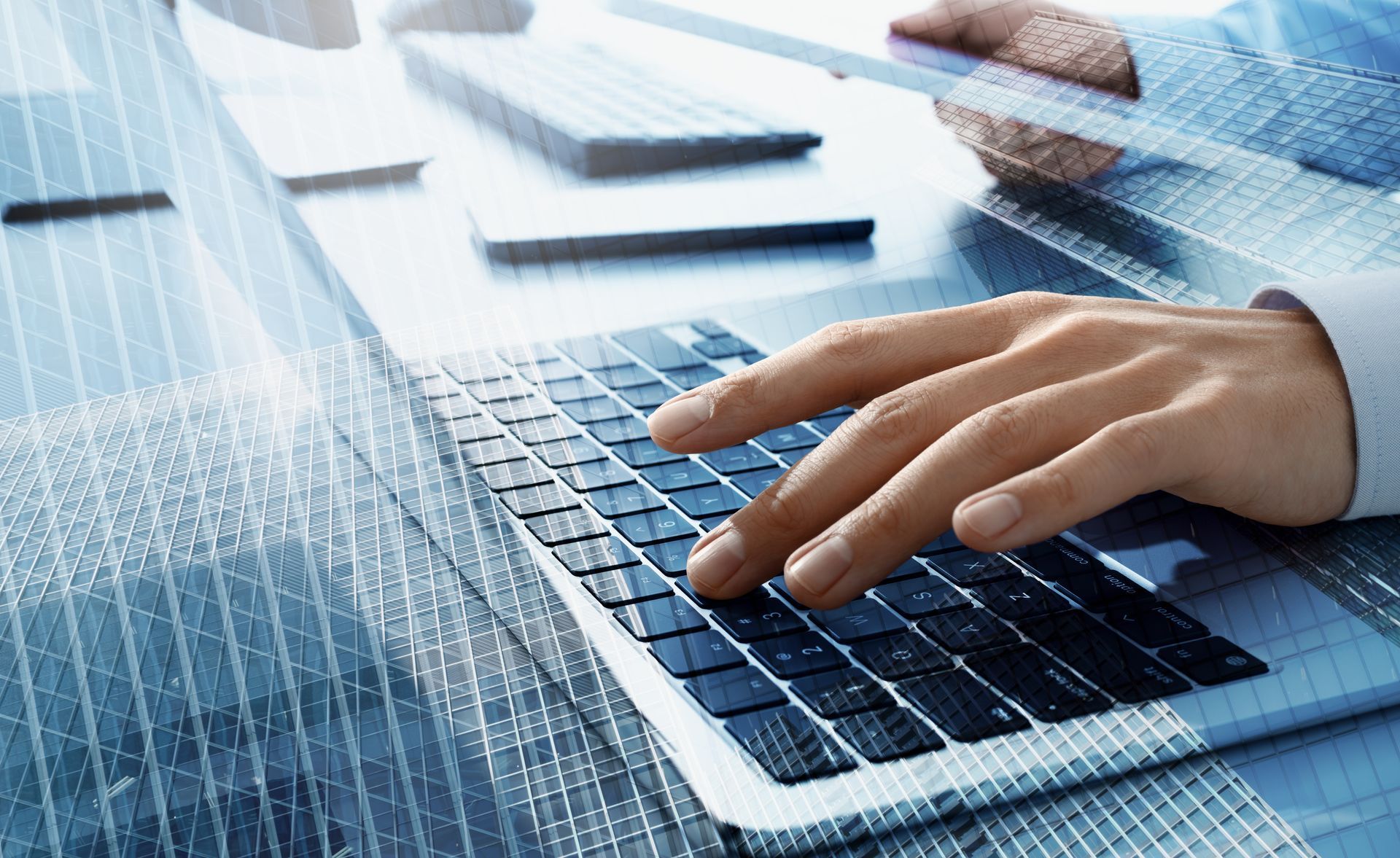 Main d'une personne tapant sur un clavier d'ordinateur portable ; palette de couleurs bleu clair et blanc, environnement de bureau.