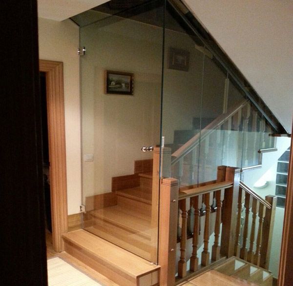 Una escalera con barandilla de cristal y escalones de madera.