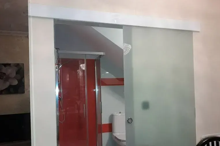 Un baño con puerta corrediza de cristal y un inodoro.