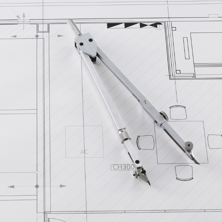 Una brújula descansa sobre un plano arquitectónico, resaltando un diseño detallado con líneas y formas.