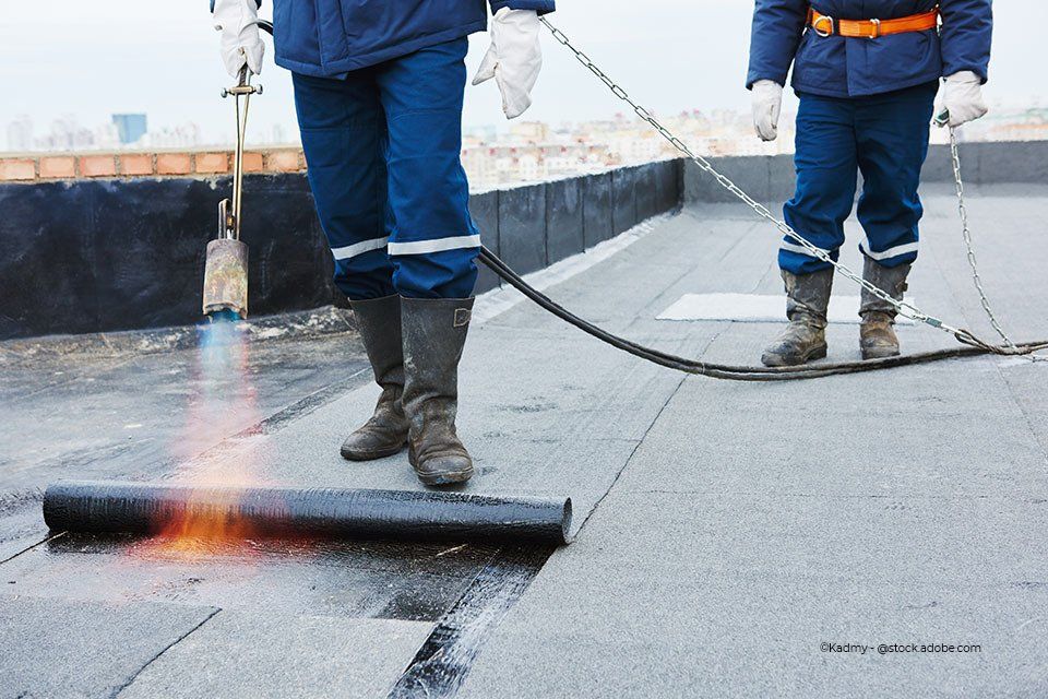 Zwei Mitarbeiter der Theodor + Ulrich Neukirchen GbR Dachdeckermeisterbetrieb schweißen Folie auf ein Dach